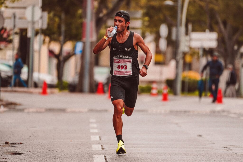 pexels-photo-10226364-10226364 Athlete running in a marathon, staying hydrated. Outdoor city street scene.